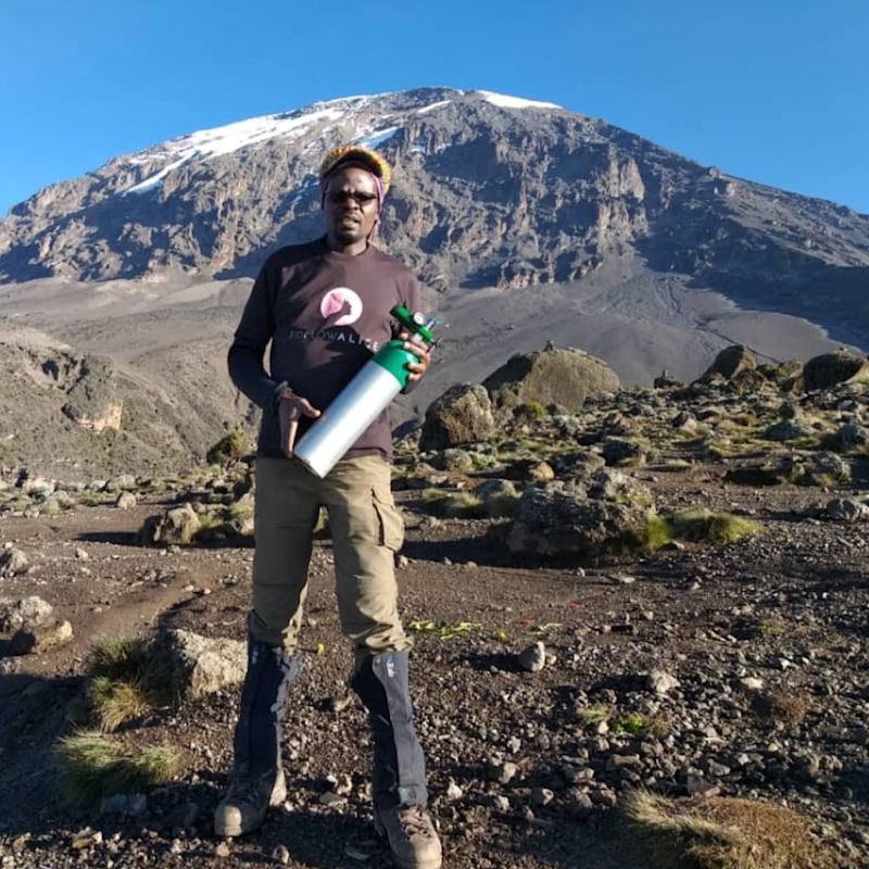 Chris on mountain with oxygen cylinder