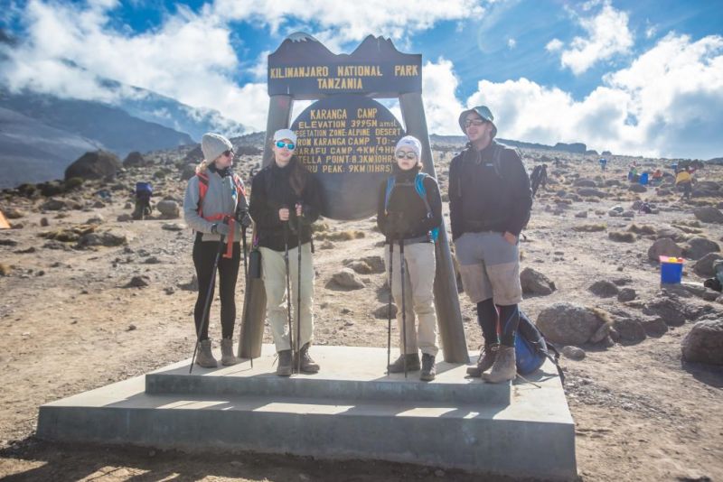 Hikers stand by sign at Karanga Camp on Kilimanjaro