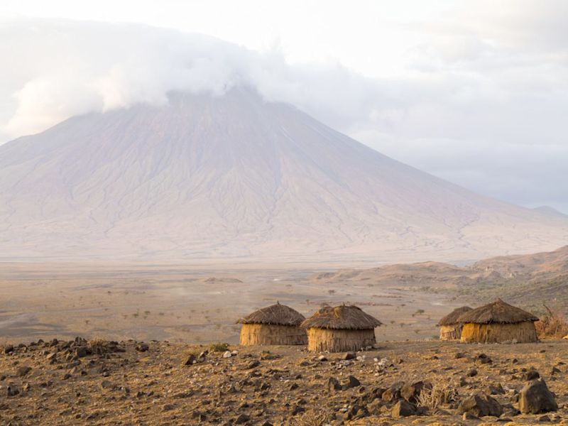 Mt Ol Doinyo Lengai with Maasai huts in the foreground