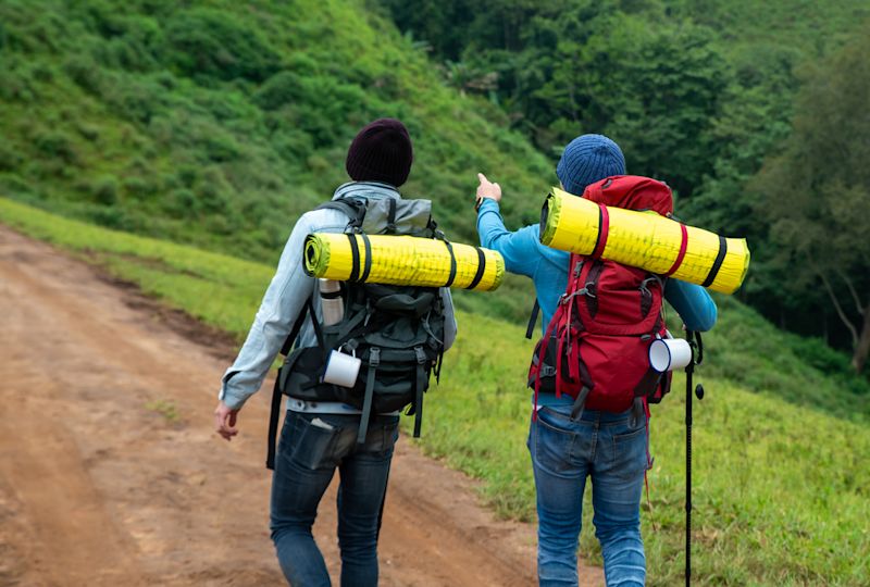 Two hikers in a green valley seen from behind with their backpacks on 