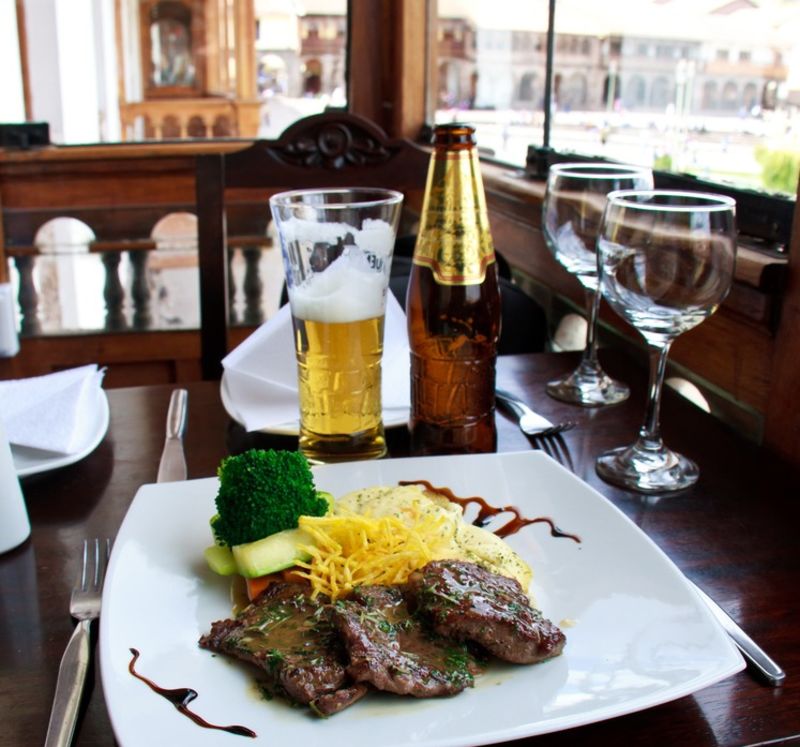 Alpaca steak and beer overlooking Plaza de Armas, food in Cusco, Peru
