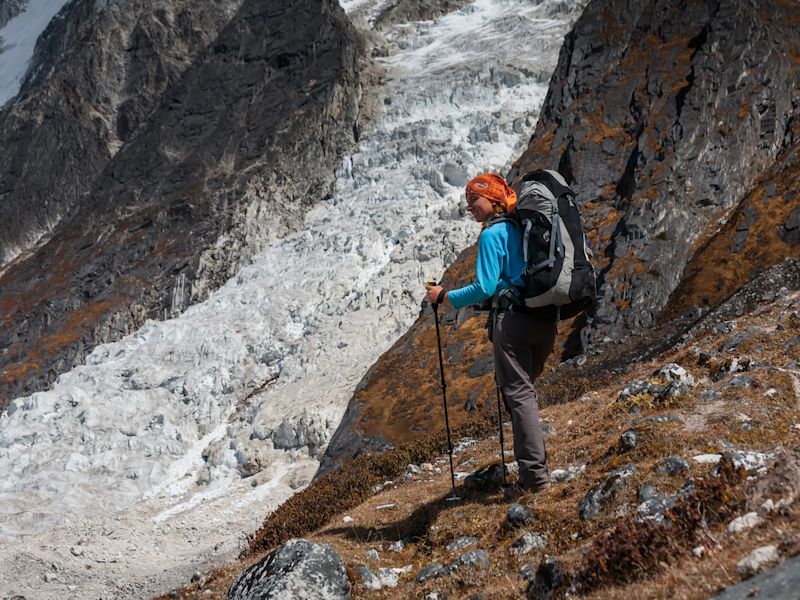 Female trekker in red bandana hikes down from Larkya La on Manaslu Circuit trek in Nepal.