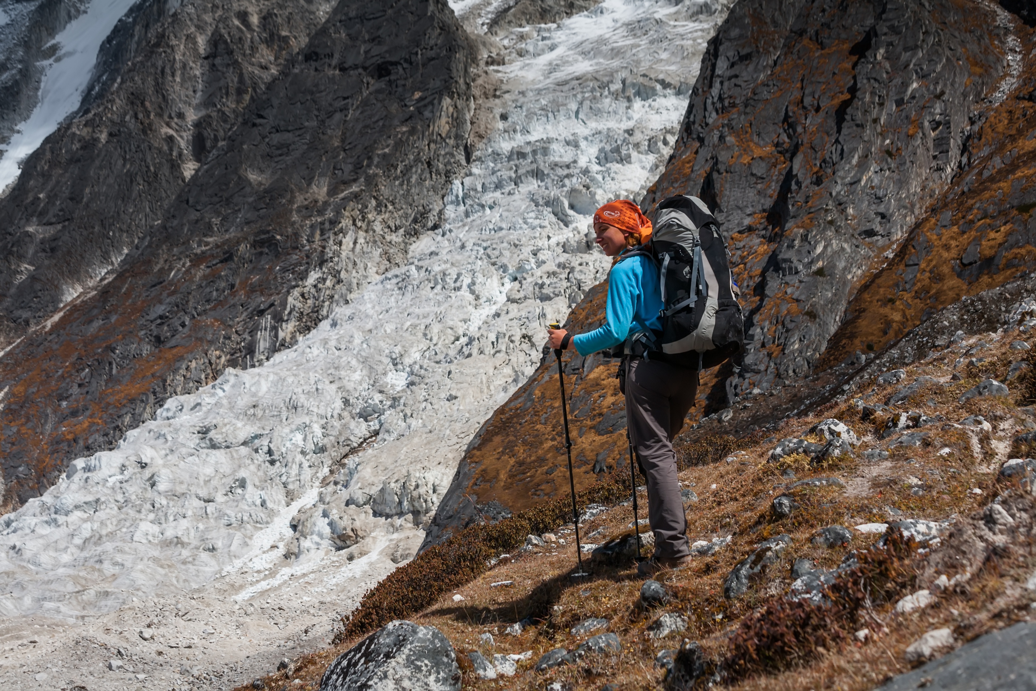 Female trekker in red bandana hikes down from Larkya La on Manaslu Circuit trek in Nepal.