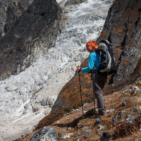 Female trekker in red bandana hikes down from Larkya La on Manaslu Circuit trek in Nepal.
