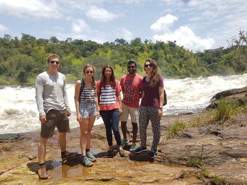 Group of young adults standing on rocks with White Nile foaming behind them