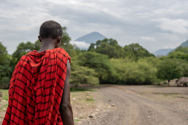 Maasai man in traditional red robe with Ol Doinyo Lengai volcano in the background