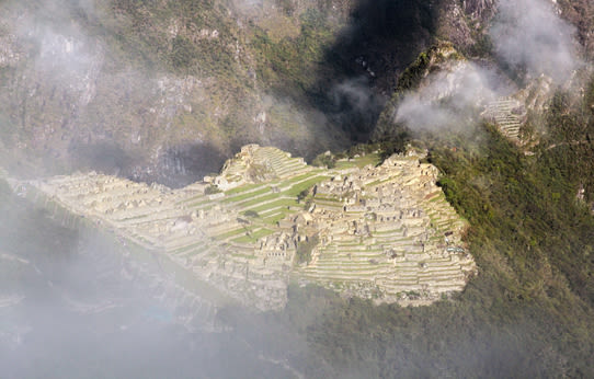 Machu Picchu citadel through clouds in the morning, seen from Sun Gate Inti Punku entrance from Inca Trail, Urubamba, Peru