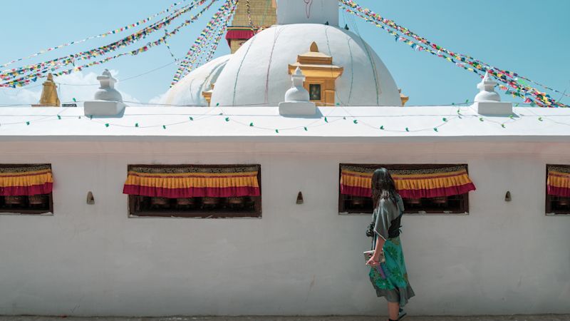 women tourist touch the bell inside the wall of Boudhanath Stupa and praying get blessing at Kathmandu, Nepal