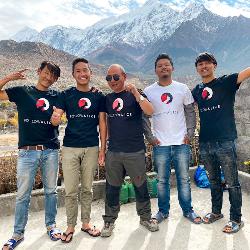 Team in Nepal stand with mountains in background