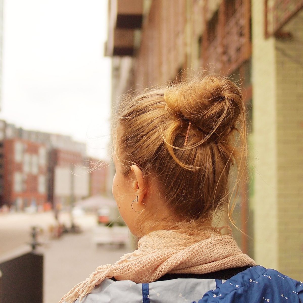 Woman with hair in a bun walking along a city street