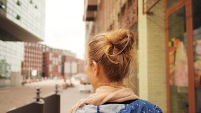 Woman with hair in a bun walking along a city street