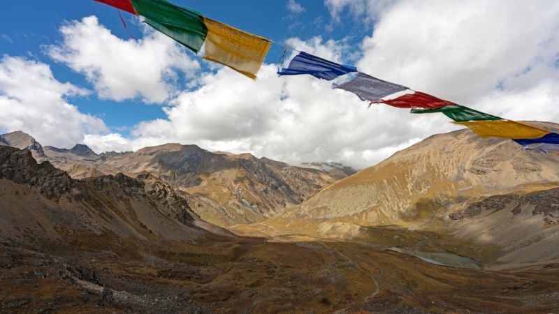 Prayer flags flutter above Nyeli La, a high-altitude pass in Bhutan along the Jomolhari and Laya treks