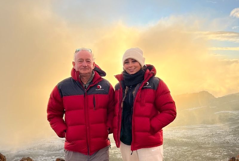 Young woman and older man at Uhuru Peak on Kilimanjaro, different ages climbers in Follow Alice jackets