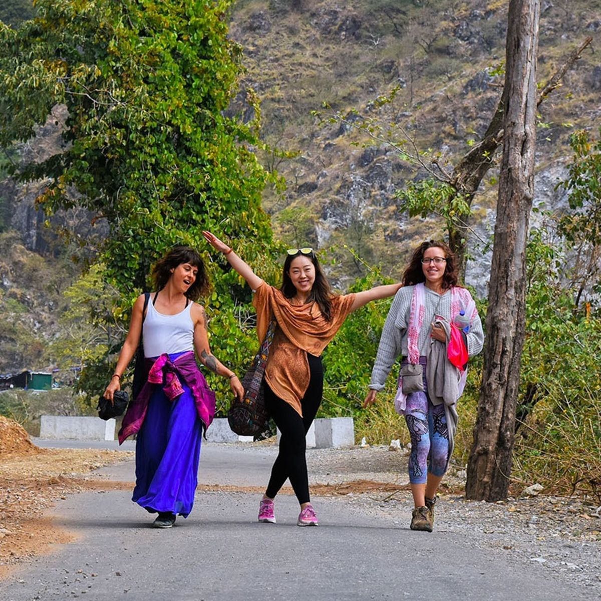 three happy women friends walking on road