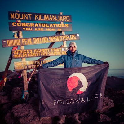 Ambassador Dan flying the Follow Alice flag at the summit of Mount Kilimanjaro