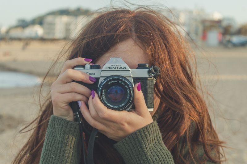 Redhead taking a photo behind a camera