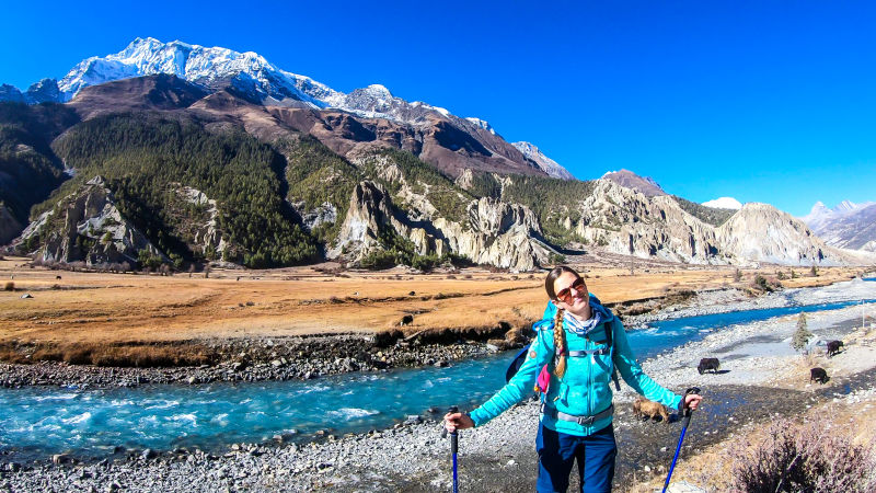 A woman with big hiking backpack admiring the view on the way to Manang, Annapurna Circuit Trek, Himalayas, Nepal