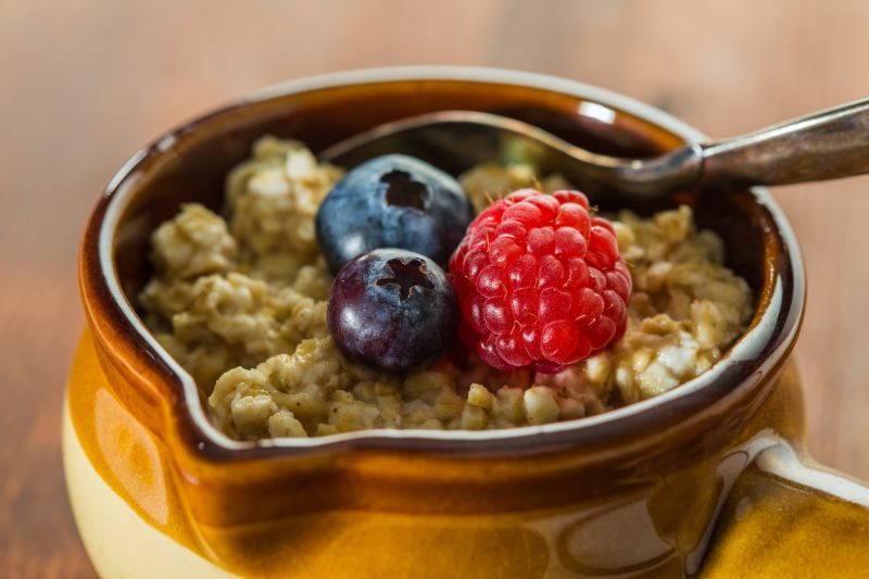 Hot oats and berries in a bowl with a spoon