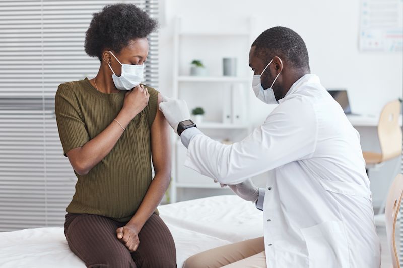 Ours. Pregnant woman receiving vaccine injection from man in lab coat