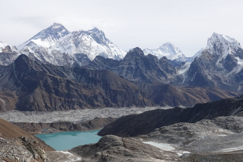 Gokyo Lake and a small settlement on its shore, surrounded by towering Himalayan peaks toped with snow