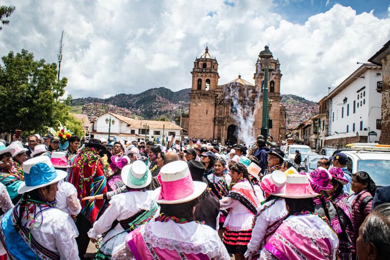 Lots of people at a street festival in Cusco with the cathedral in the background, Peru