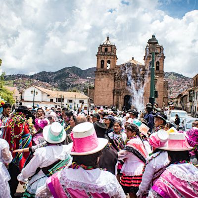 Lots of people at a street festival in Cusco with the cathedral in the background, Peru
