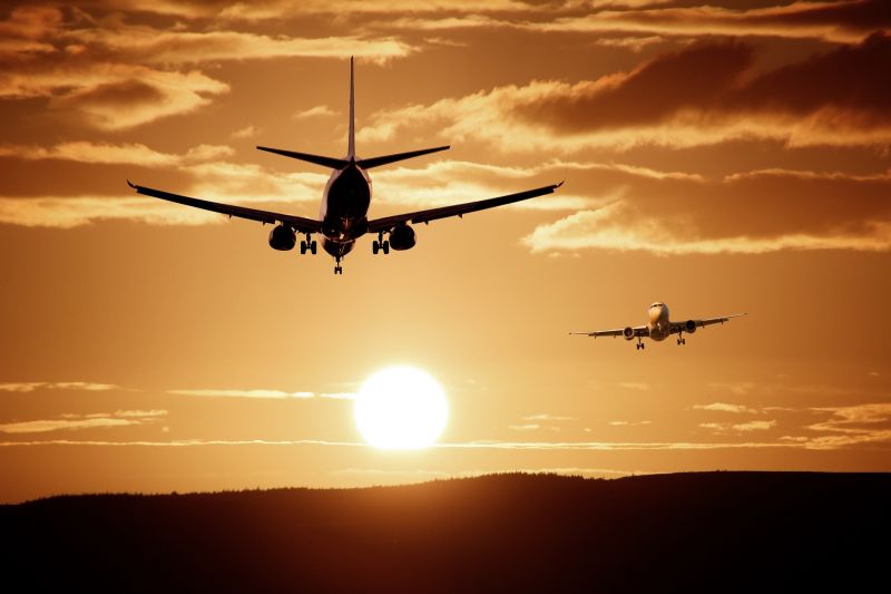 Two airplanes in flight with large setting sun