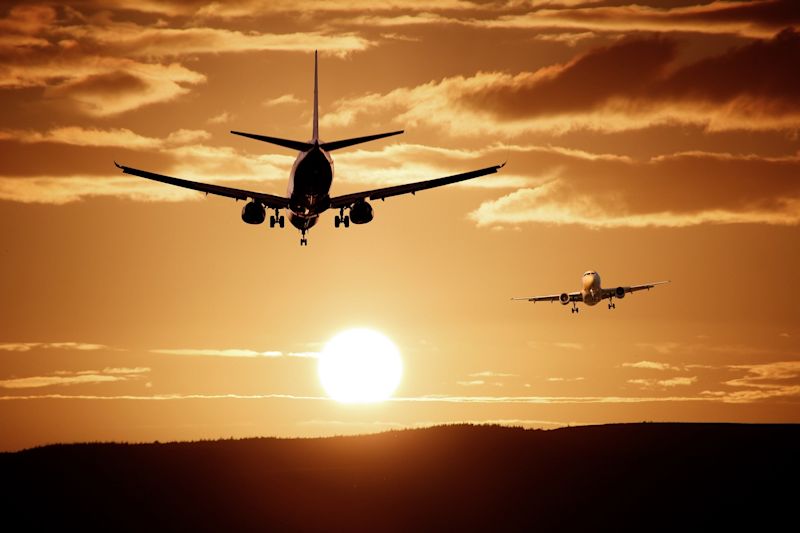 Two airplanes in flight with large setting sun