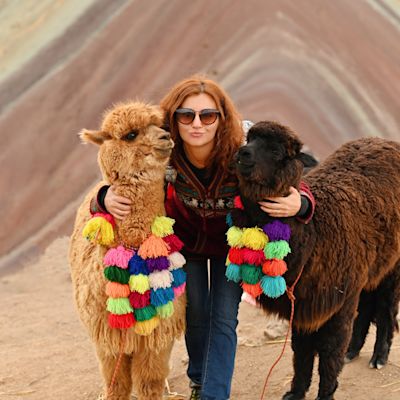 Young red haired girl with two cute llamas at Vinicunca Rainbow Mountain, Peru
