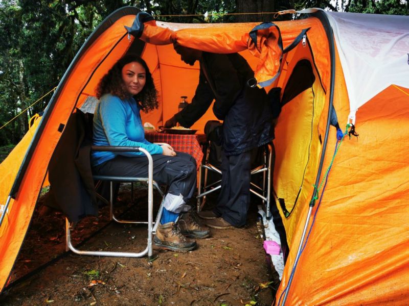 Lady sitting inside small orange tent on Kilimanjaro