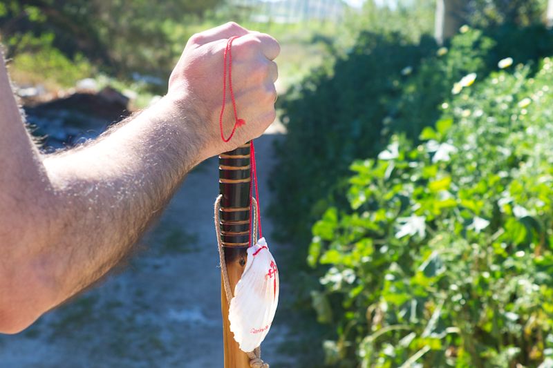 Close up of forearm and top half of walking staff and road shell of male pilgrim on way to Santiago