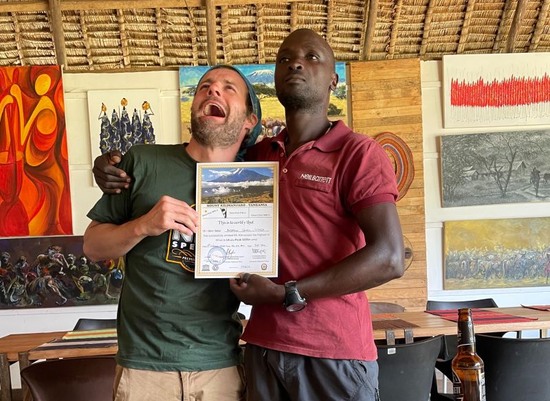 Kilimanjaro trekker with his guide and completion certificate putting on funny expressions