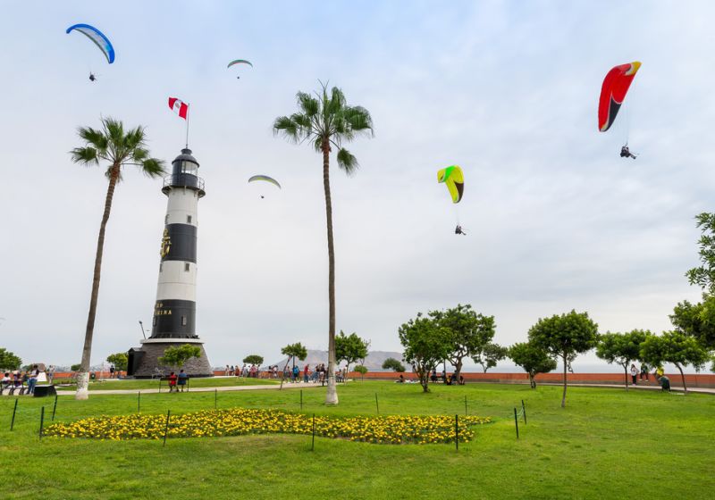 View of La Marina Lighthouse (Faro de La Marina) in Miraflores district, with some paragliders in the sky, in Lima Peru 