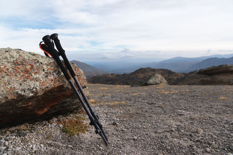 Telescoping trekking poles leaning against a rock in the mountains