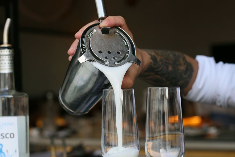 Bartender pouring pisco sour into a glass