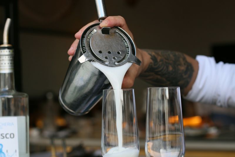 Bartender pouring pisco sour into a glass