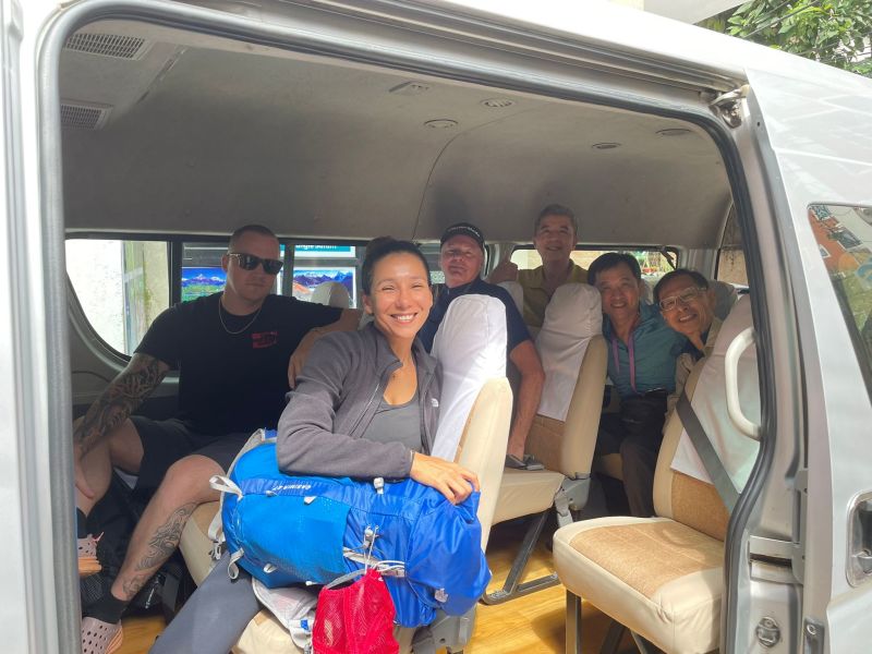 Group of smiling adults seated in a van headed to the airport in Nepal