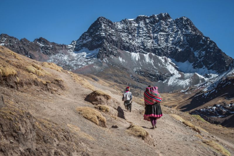 Lady with traditional clothes walk with her son between the Andean mountains in the Salkantay trek going to Machu Picchu, Peru