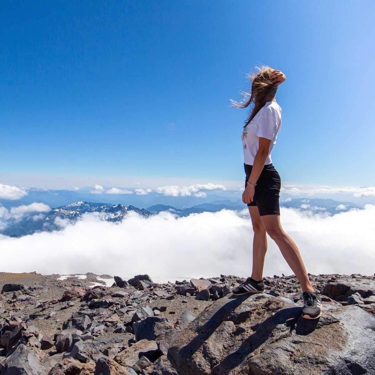 Woman standing above clouds in the wind