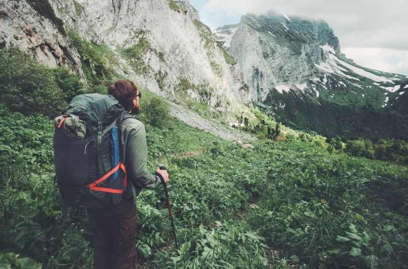 Male hiker in mountains with trekking poles and a backpack