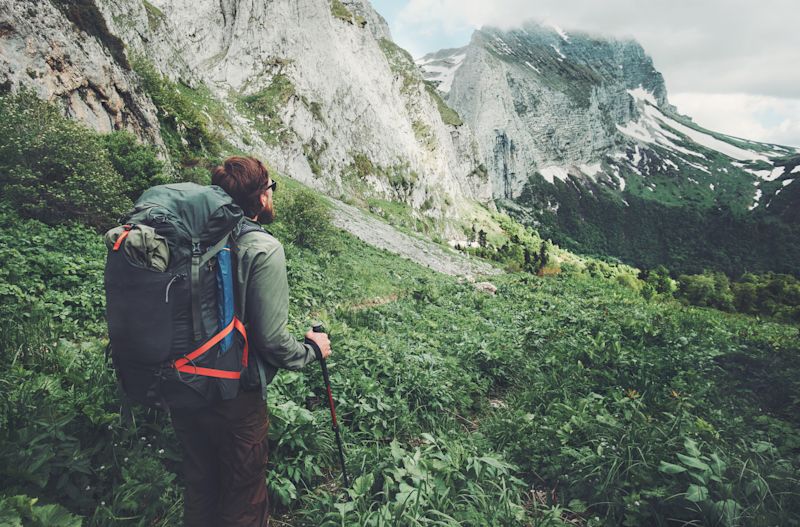 Male hiker in mountains with trekking poles and a backpack