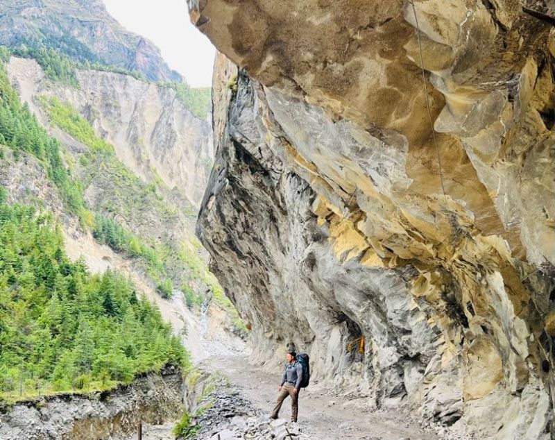 Annapurna Circuit trail, hiker below overhanging cliff