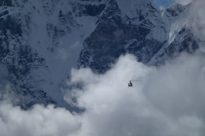 Picture of a rescue helicopter over big clouds, Gorakshep, EBC trek, Nepal
