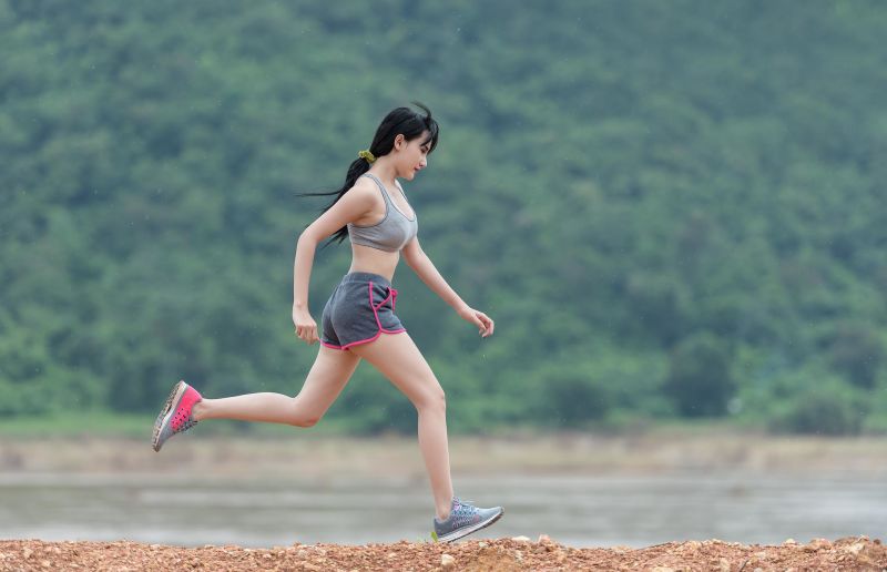 Asian woman running by river