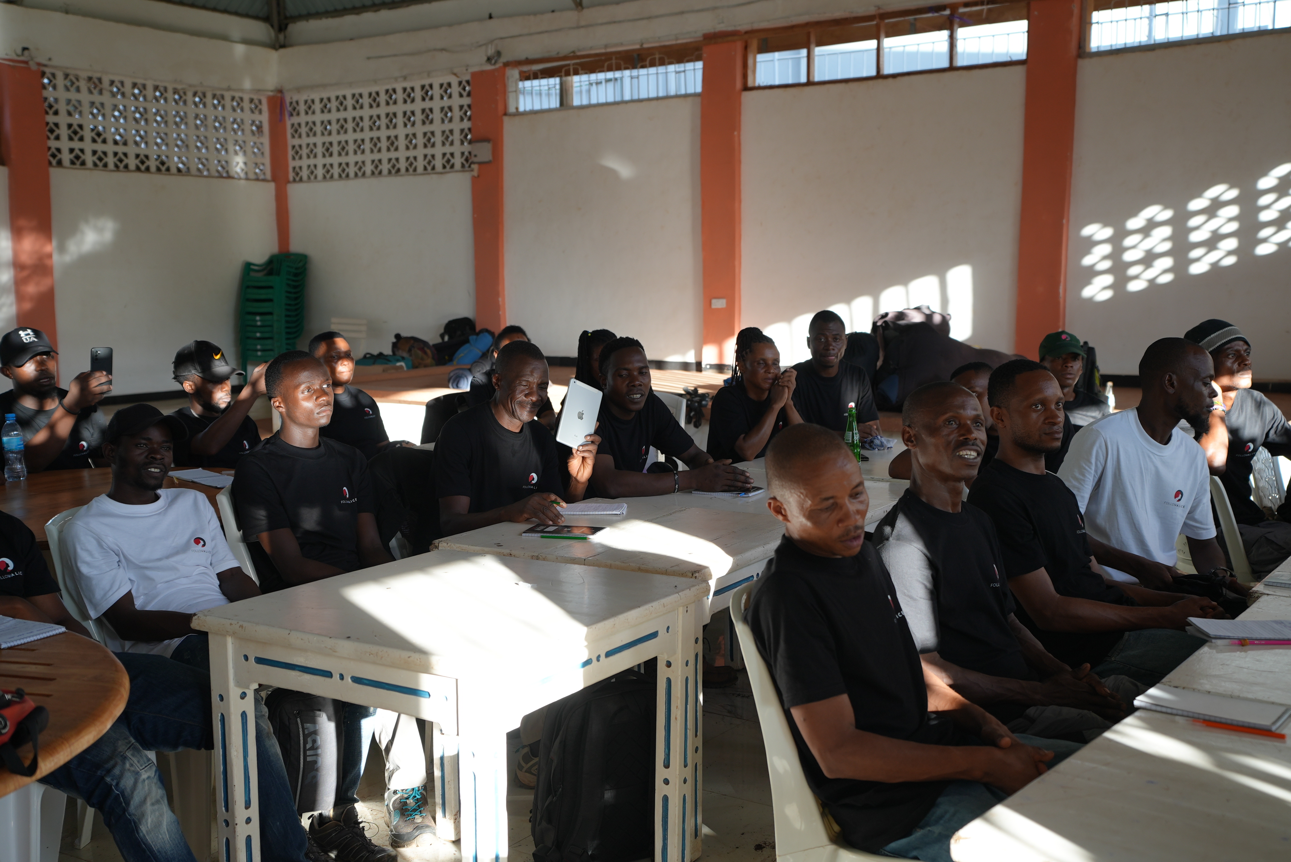 Follow Alice porters during first aid training, seated at tables, listening to lecture