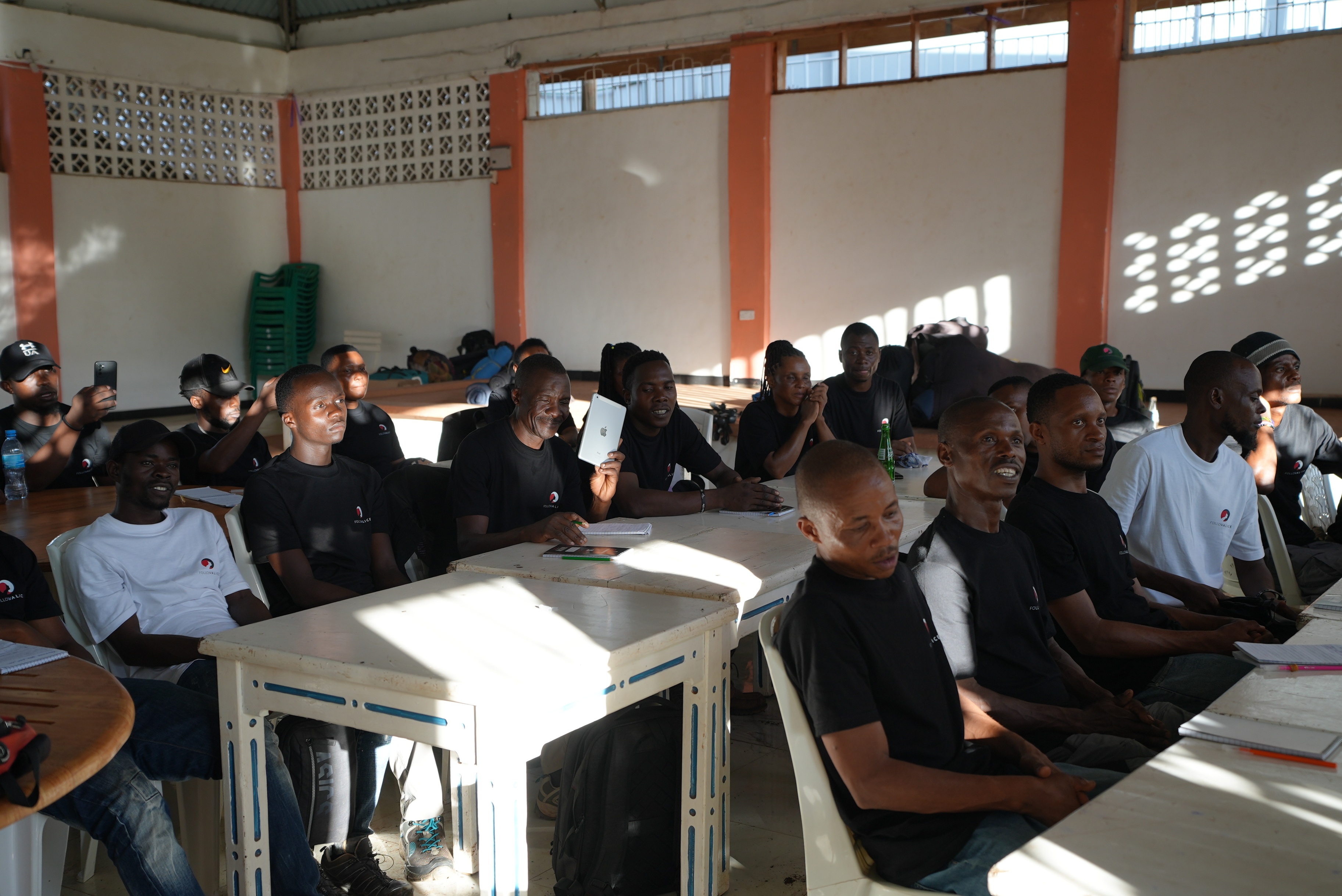 Follow Alice porters during first aid training, seated at tables, listening to lecture