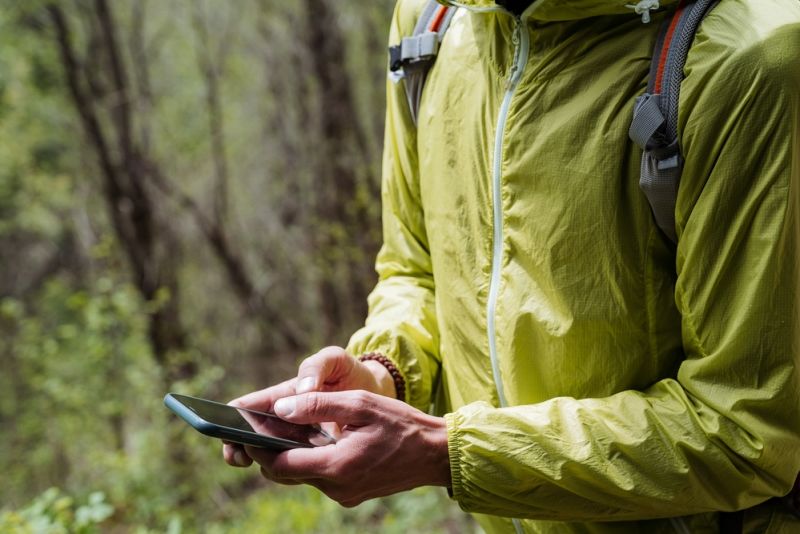 Close up in forest of hiker holding cellphone