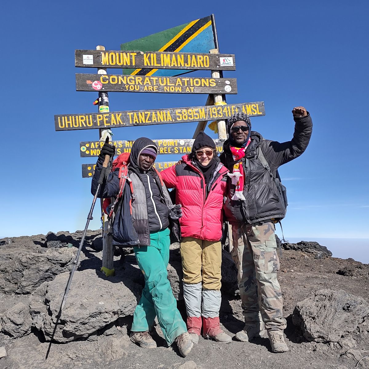 Trio of trekkers at Uhuru Peak on Kilimanjaro, Tanzania