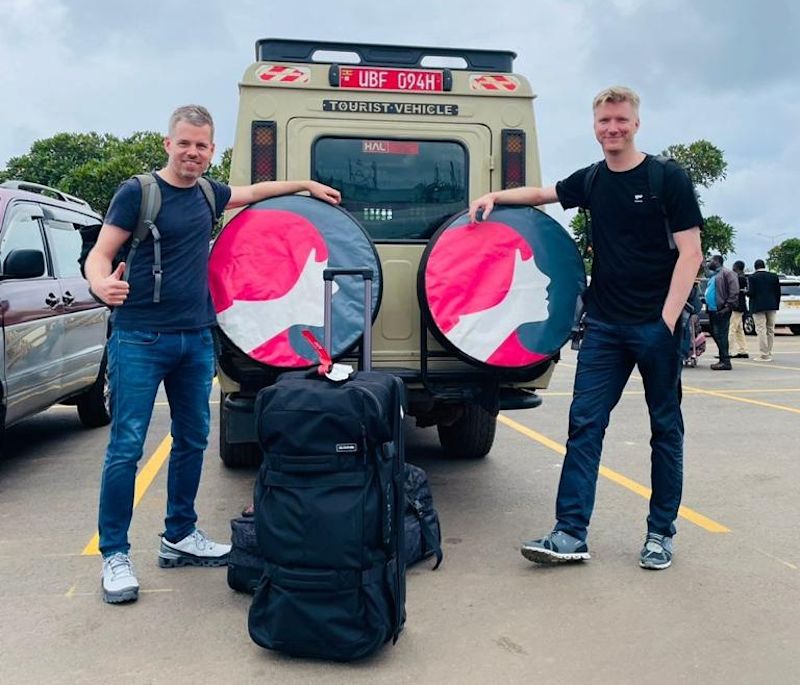 Two men standing by a 4x4 safari vehicle with the FA logo on wheel covers, Uganda