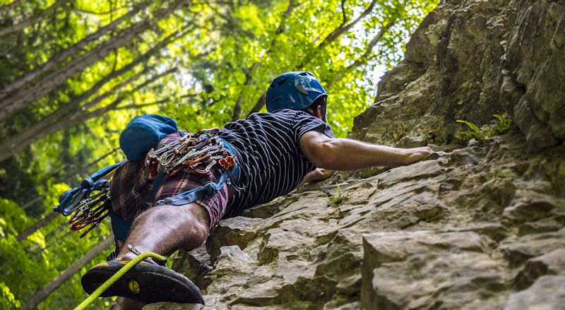 Man climbing rock face from below